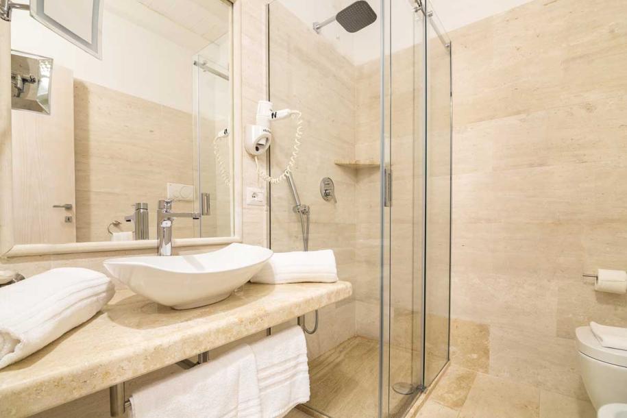 Elegante bagno moderno con doccia in vetro e lavabo su piano in marmo.